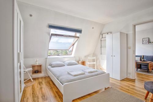 a white bedroom with a bed and a window at Appartement classé 2 étoiles à Cabourg - Proche plage et centre-ville in Cabourg