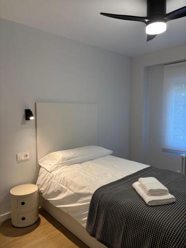una camera da letto con un letto con lenzuola bianche e un ventilatore a soffitto di Apartamento Bailatús a Saragozza