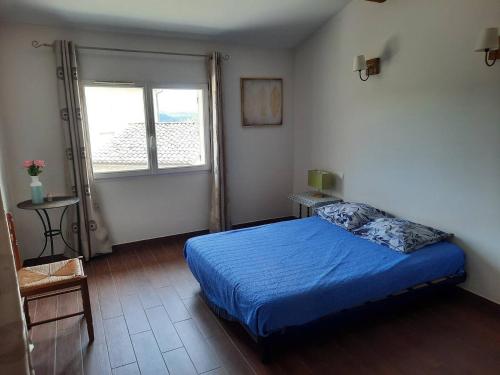 a bedroom with a blue bed and a window at Maison au coeur d'un domaine viticole in Cornillon