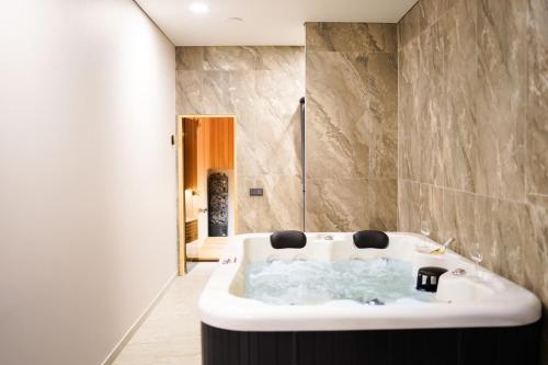 a bathroom with a white tub and a shower at Svaja ApartHotel in Šiauliai