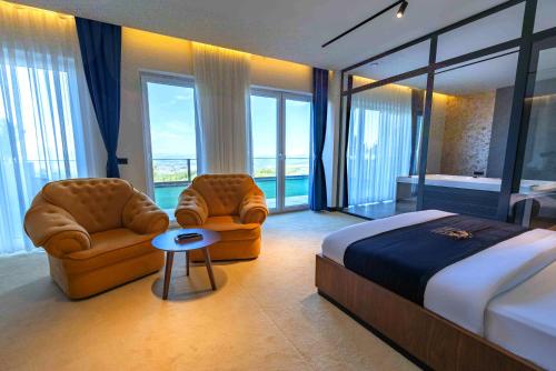 a bedroom with two chairs and a bed and windows at Iliria Hill Resort & Spa in Orllan