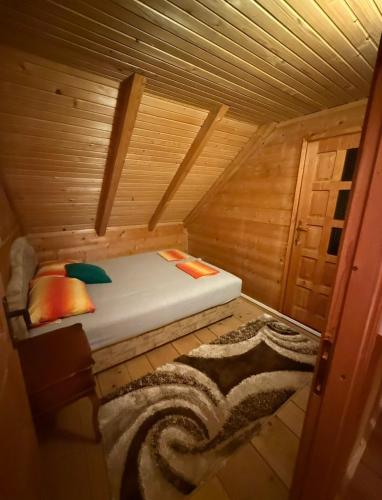 a small bed in a wooden cabin with a rug at Vikendica za odmor in Dobra Voda