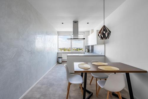 a kitchen with a wooden table and white chairs at Urban Oasis Stodůlky in Prague
