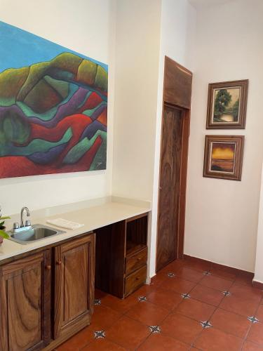 a kitchen with a sink and a painting on the wall at Las Golondrinas El Zonte, El Salvador in El Zonte