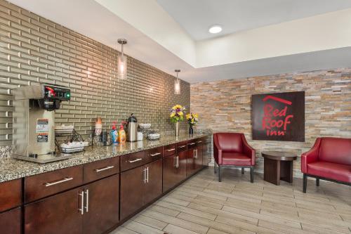 a kitchen with a counter and two red chairs at Red Roof Inn Baton Rouge in Baton Rouge