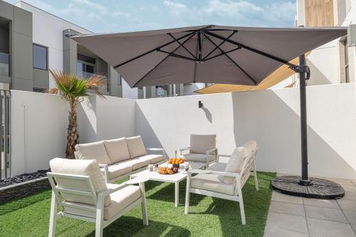 a patio with a table and chairs and an umbrella at Upscale 4BR Villa, Bali Pool, Resort Escape in Dubai