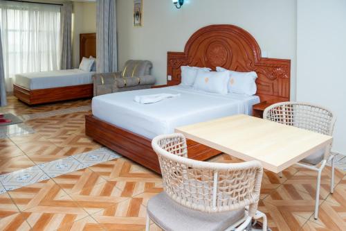 a bedroom with a bed and a table and chairs at The Mark Hotel in Ruiru