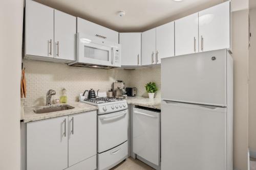 a kitchen with white cabinets and a white refrigerator at Oasis Apartment in the Heart of Union Square Downtown Manhattan in New York