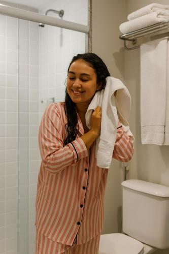 a woman in a bathroom holding a towel at Flat IATE CLUBE Home Experience Praia do Canto in Vitória