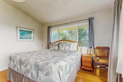 a bedroom with a bed and a window and a chair at Hale ʻAina Kai in Kuhio Village