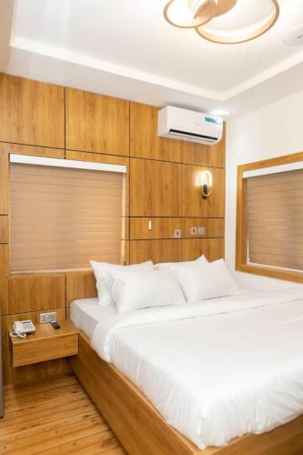 a bedroom with a large white bed and wooden walls at Steeze Apartment in Mama