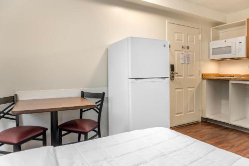 a kitchen with a white refrigerator and a table at Birch Hill Suites Louisville in Louisville