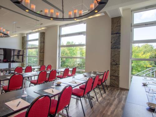 a dining room with tables and red chairs at Hasseröder Burghotel in Wernigerode