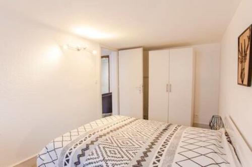 a white bedroom with a bed and white cabinets at Le Rapp - Historic Center - Bright - 60m 2 in Colmar