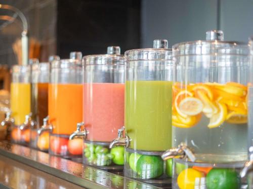 Una fila de frascos de vidrio llenos de jugos de diferentes colores. en Pullman Adelaide, en Adelaida