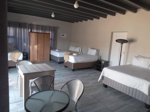 una camera d'albergo con due letti, un tavolo e delle sedie di K4 Bed and Breakfast a Maseru