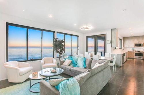 a living room with a couch and a kitchen with windows at Waterfront Haven with Spectacular View in Bainbridge in Rollingbay