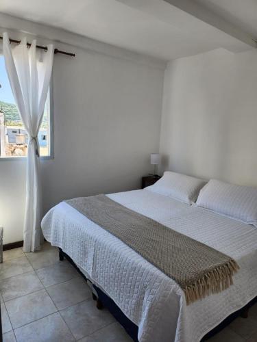 a white bedroom with a bed and a window at Alma Jujeña in San Salvador de Jujuy