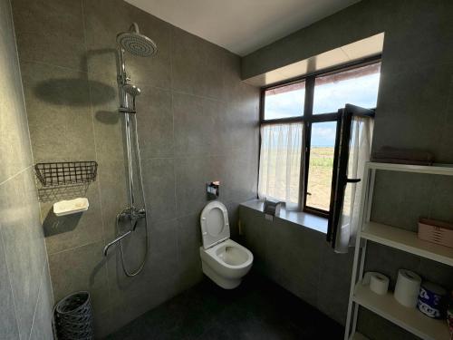 a bathroom with a shower and a toilet and a window at Red House in Chok-Tal