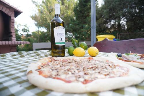 a bottle of wine sitting on a table with a pizza at Appartements Lena. in Premantura