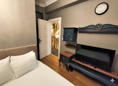 1 dormitorio con 1 cama, TV y reloj en Valide i Suit, en Estambul