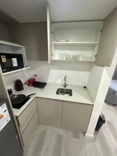 eine kleine Küche mit Spüle und Mikrowelle in der Unterkunft MOVISTAR ARENA PREMIUM THAMES 56 8 piso 812 Cocheras y Seguridad in Buenos Aires