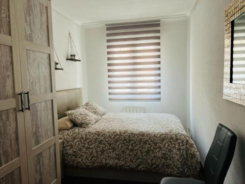 a bedroom with a bed and a window with blinds at Apartamento El Pedregal in Castro-Urdiales