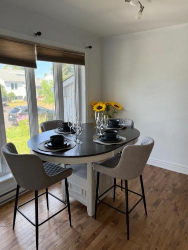 a dining room with a table with chairs and flowers at Chambre à louer proche de Montréal in Sainte-Catherine
