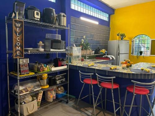 a kitchen with blue and yellow walls and stools at Capacabana in Bacalar