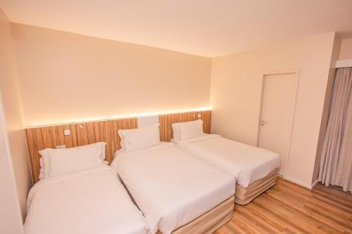 two beds in a small room with white sheets at Quality Hotel Aracaju in Aracaju