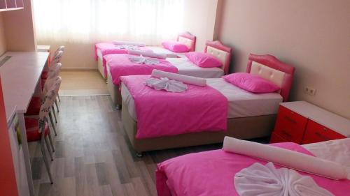 een groep van vier bedden in een kamer met roze lakens bij Simperia in Safranbolu