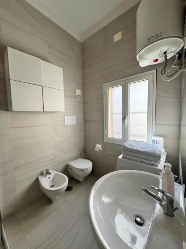 a white bathroom with a sink and a toilet at Casetta Silvia in Brindisi