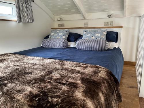 a bedroom with a bed with blue sheets and pillows at Shepherds Cabin at Titterstone in Farden