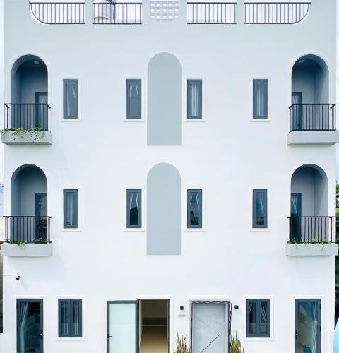 - un bâtiment blanc avec des fenêtres et des balcons dans l'établissement DI HOME I HOMESTAY PHAN THlẾT, à Ấp Bình Hưng