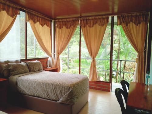 a bedroom with a bed in front of windows at Mashpi Amagusa Lodge in Mashpi