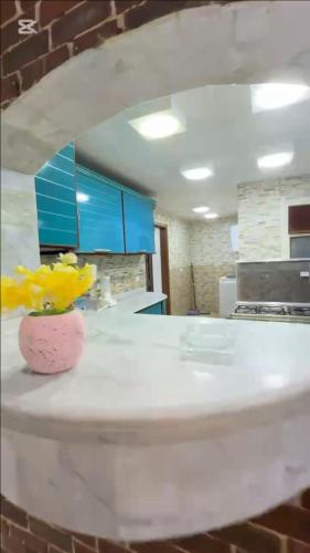 un mostrador de cocina con un jarrón con flores amarillas. en KHadma vip, en Banī Ghālib