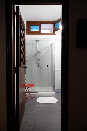 baño con ducha y taburete rojo en Pompei Rooms and Apartment, en Pompeya