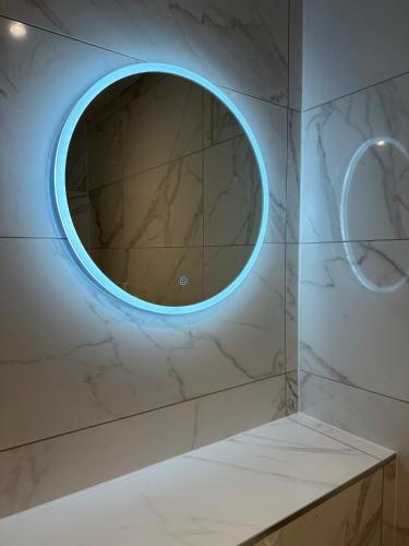 a round mirror on a wall with a marble floor at The Apollo Apartments in Saint Neots