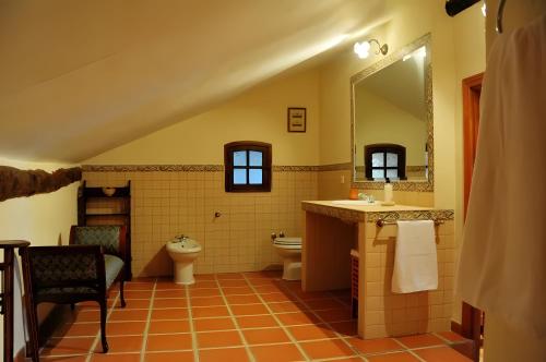 Un baño con lavabo, inodoro y espejo. en El Escondite de Los Duendes, en Tanarro