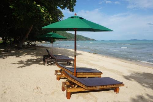two lounge chairs and an umbrella on a beach at The Tropical Beach Resort in Ko Chang