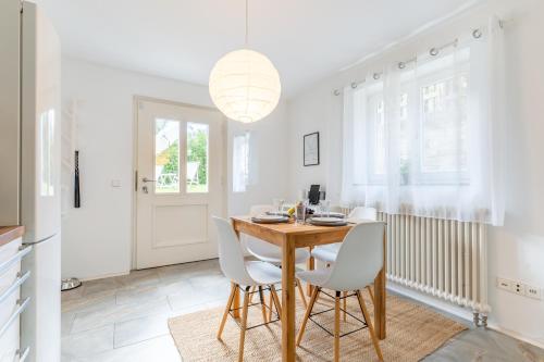 a dining room with a wooden table and white chairs at Bodensee Gateway - Stockach in Stockach