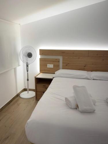 a bedroom with a bed with two pillows and a fan at Ático el YELMO - Hotel Ruta del Segur in Pontones