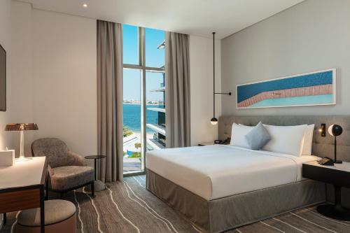 Una habitación de hotel con una cama, un escritorio y una ventana. en Th8 Palm Dubai Beach Resort, Vignette Collection by IHG, en Dubái