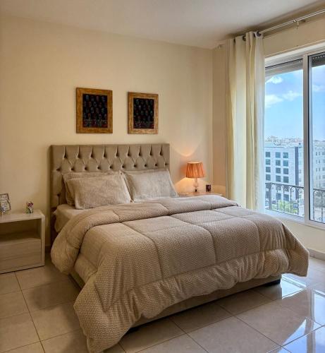 a bedroom with a large bed with a large window at Exquisite & inviting 2 Bedroom 2 bath Balcony Fast internet in Amman