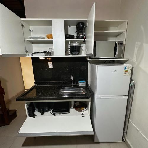 a small kitchen with a sink and a refrigerator at Apartamento completo AC & Cozinha - centro Brotas - SP in Brotas