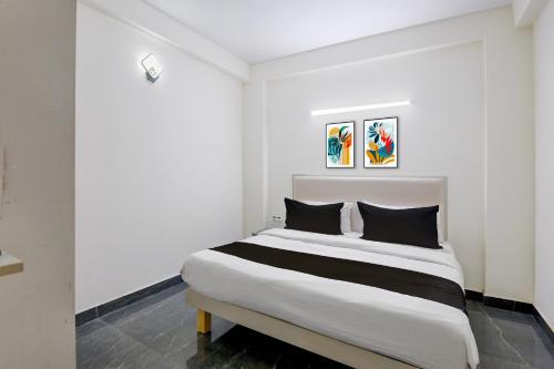a white bedroom with a large bed with black pillows at Hotel O Kalka in Indraprast