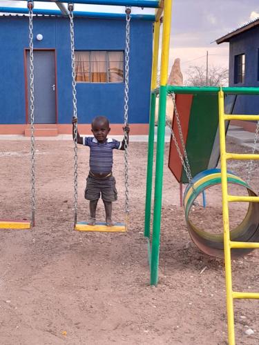 a young boy on a swing at a playground at Ansta Farmhouse Self Catering Camping Nursery in Outjo