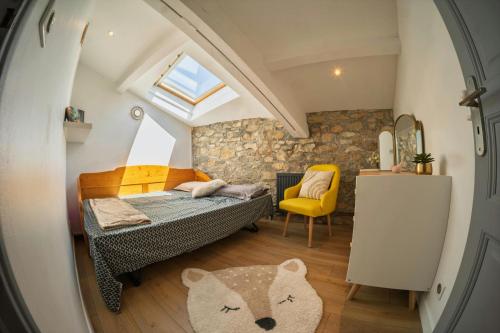 ein kleines Schlafzimmer mit einem Bett und einem gelben Stuhl in der Unterkunft La Maison du Lavoir Charme & Nature proche de Lyon in Saint-Quentin-Fallavier