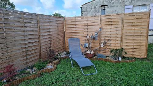 a blue chair in a yard next to a fence at Gîte Le Logis du Tilleul in Plassay