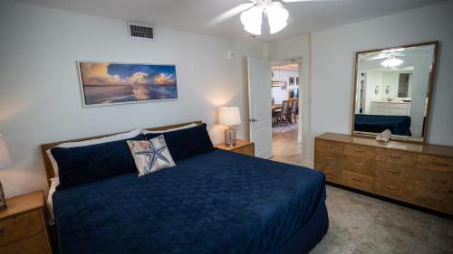 een slaapkamer met een blauw bed en een spiegel bij Beachfront Luxury with Spectacular Ocean Views! in Ormond Beach